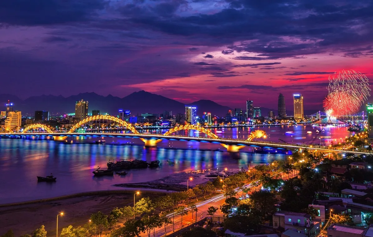 Pháo hoa bung trên sông Hàn nhìn từ xa, cầu Rồng sáng đèn ở tiền cảnh